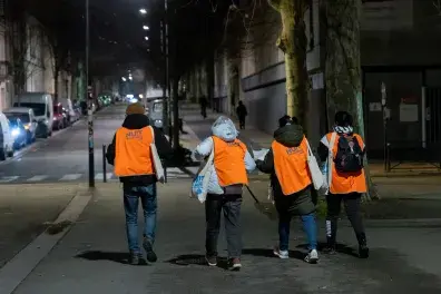 Photo de quatre bénévoles de la Nuit de la solidarité vues de dos, marchant dans la rue.