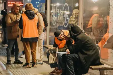 Photo de bénévoles de la Nuit de la solidarité discutant avec des personnes sans abri à un arrêt de bus.