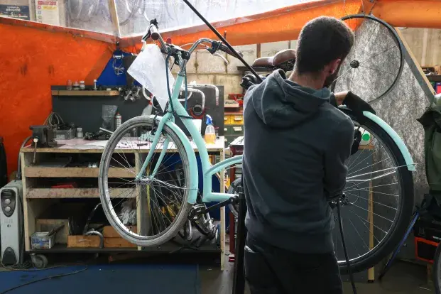 Un homme répare un vélo.