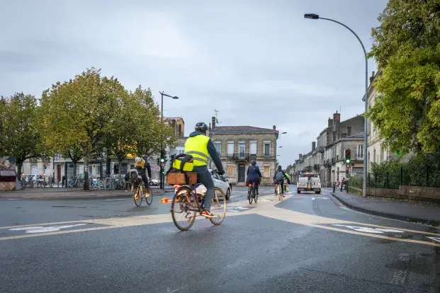 Photo des cyclistes qui roulent sur une piste dédiée aux vélos et sont équipés d'un casque et d'une chasuble jaune..