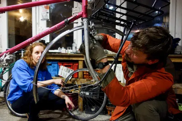Deux personnes réparant un vélo de seconde main