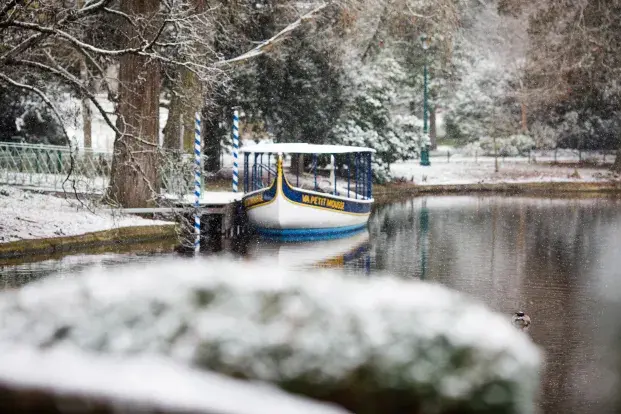 Un bateau amarré sur un étang enneigé, dans un décor hivernal paisible.