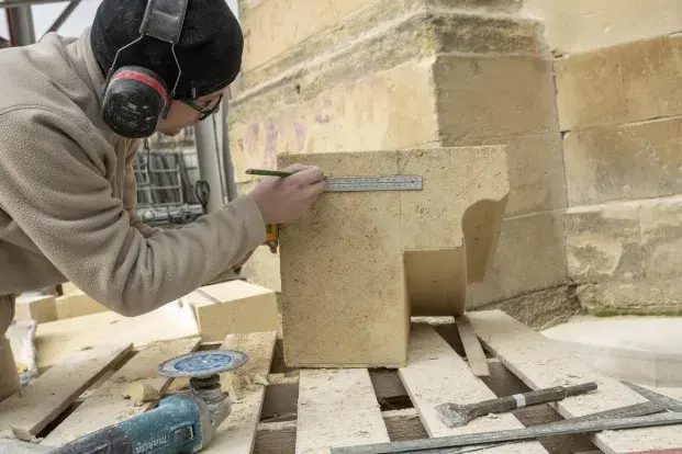 Photo d'un tailleur de pierre au travail sur le chantier de la flèche Saint-Michel.