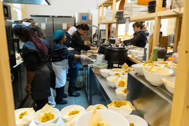 Des cuisinières préparant des plats dans la cuisine de la Manuco