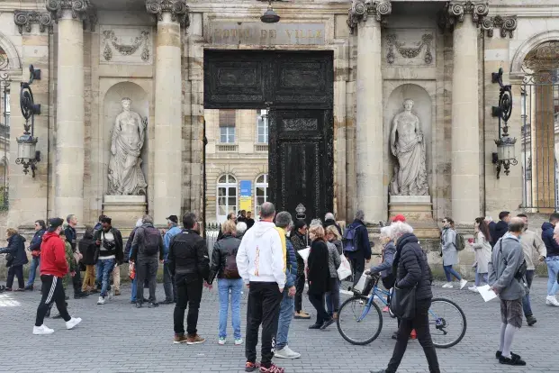 Photo de Bordelais devant la porte calcinée de l'hôtel de ville de Bordeaux.