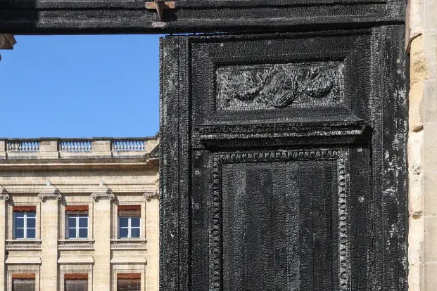 Photo de la porte de l'hôtel de ville ouverte,  son bois est calciné.