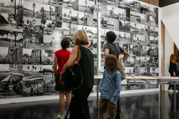 Quatre personnes regardent des photographies en noir et blanc sur un mur