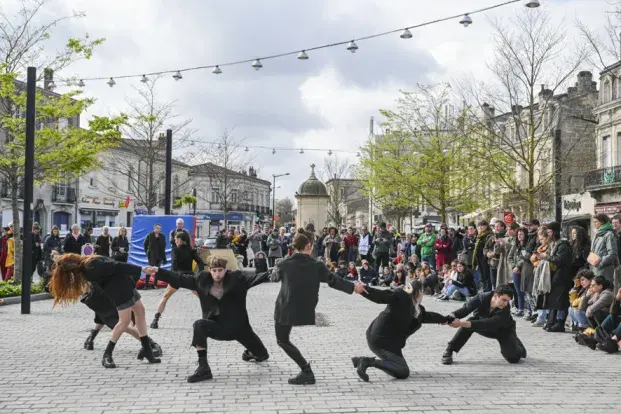 des danseurs habillés en noir sur la place nansouty, de dos, avec du public autour