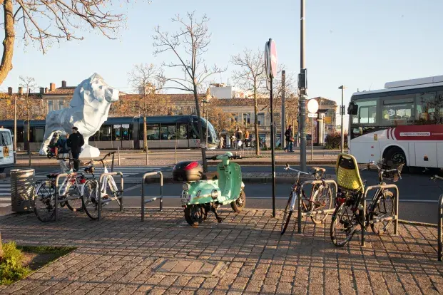 photo d'habitants sur la place Stalingrad à Bordeaux, avec la statue d'un lion bleu en arrière-plan.