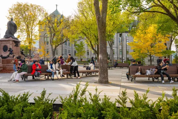 Des personnes assises sur des bancs dans le jardin de l'Hôtel de ville de Québec