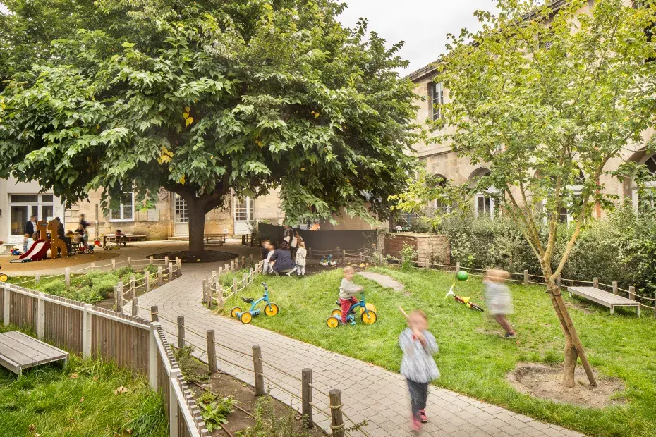 Photo de la cour d'école Barraud végétalisée avec des enfants qui jouent.
