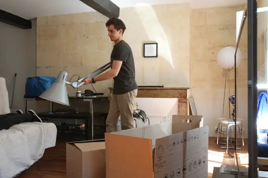 Un homme porte une lampe pendant un déménagement.