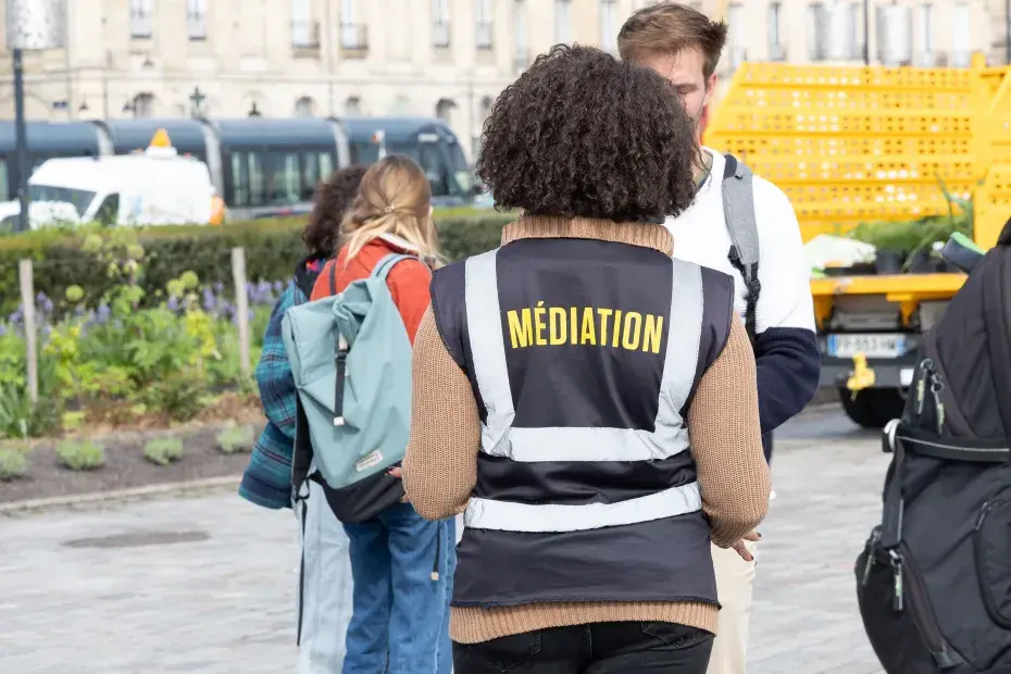 Photo d'une médiatrice de dos, parlant avec un habitant.