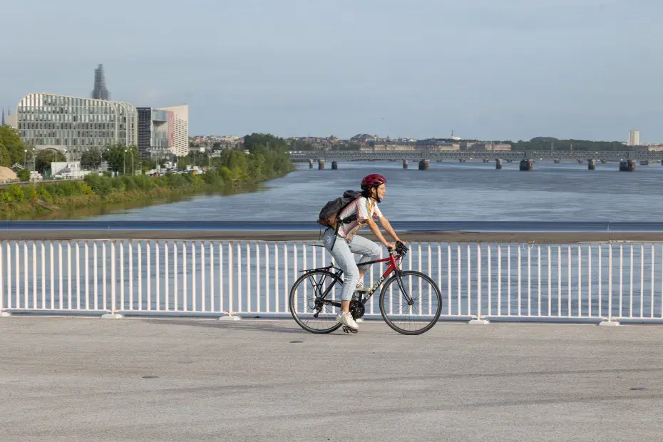Photo d'une cycliste qui traverse à vélo le nouveau pont Simone Veil en direction de la rive droite.