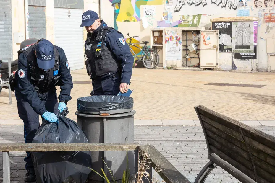 Deux agents de la brigade anti-incivilité vérifient un sac poubelle déposé sur la voie publique.