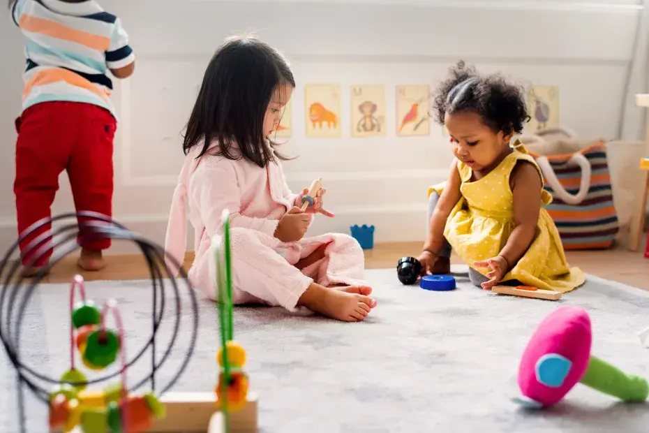 Deux enfants jouent ensemble en intérieur au milieu de jouets.
