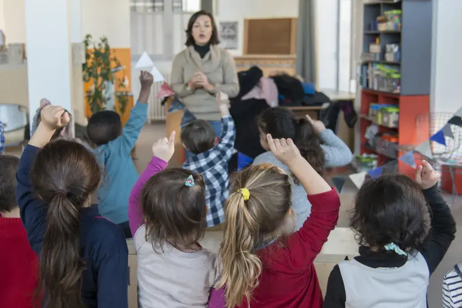 Des élèves de maternelles lèvent le doigt pour participer à un atelier.