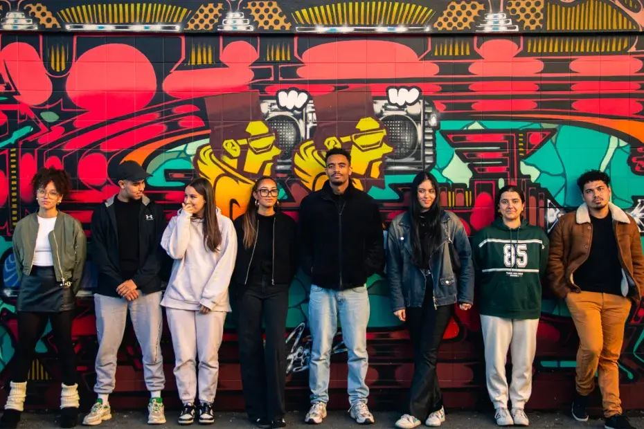 Un groupe de jeunes pose devant une fresque murale colorée