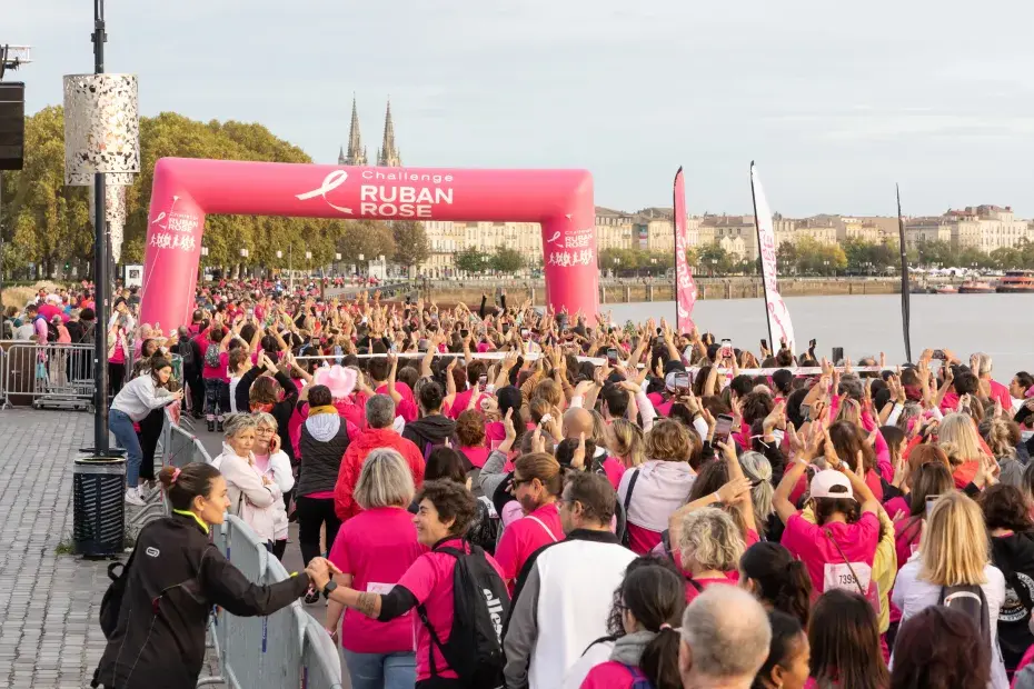Une foule passe sous une arche pour la course contre le cancer du sein.