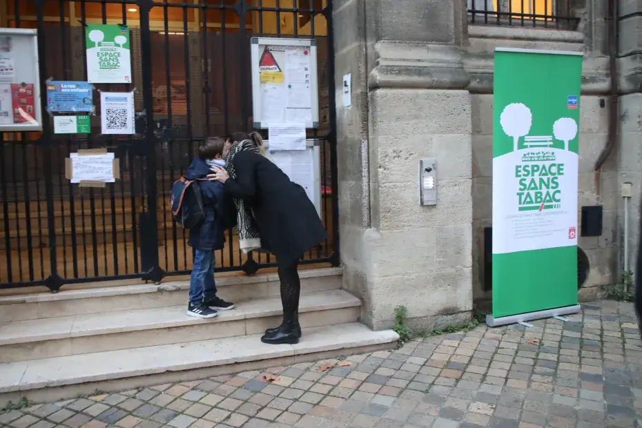 Une maman embrasse son fils devant un espace sans tabac.