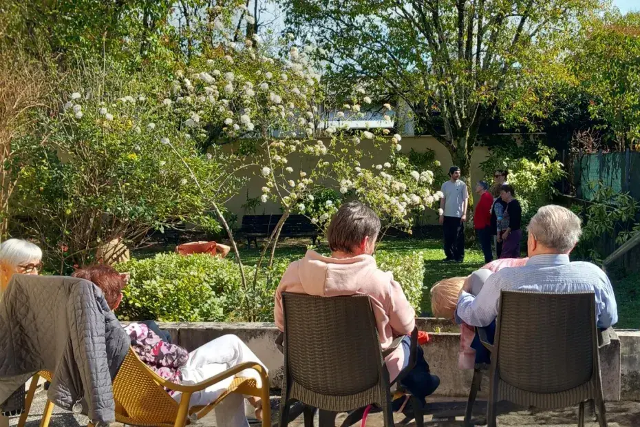 Quatre personnes âgées de dos profitent du soleil sur une terrasse.