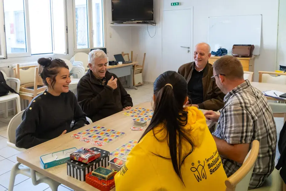 Des jeunes adultes et des seniors jouent ensemble aux cartes.