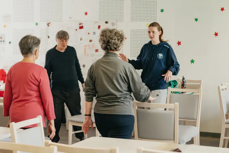 Trois seniors suivent un cours de sport avec une coach.