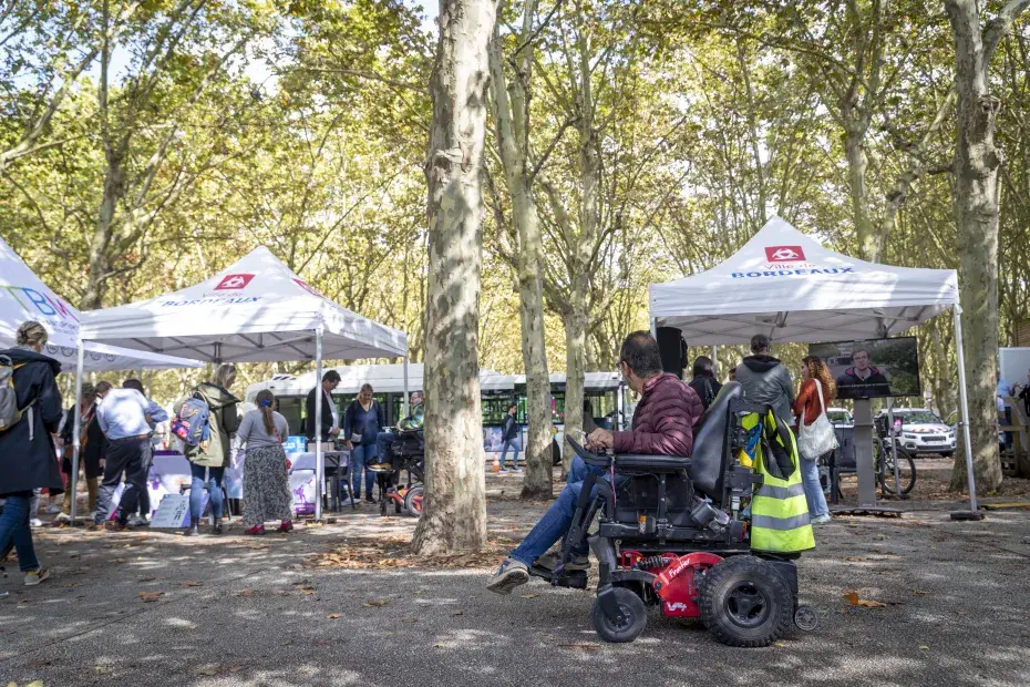 Un personne en fauteuil roulant regarde les stand de la Ville de Bordeaux.