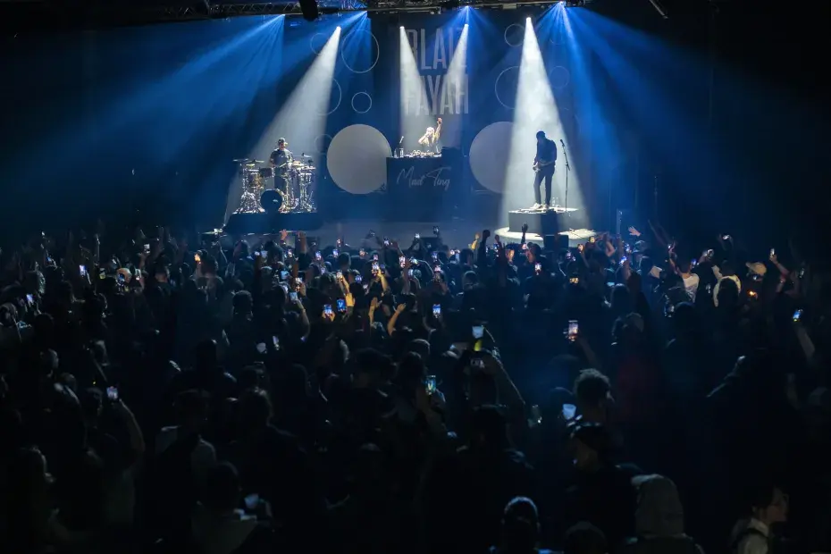 photo d'un concert de rock avec du public, les lumières sur la scène sont dans les teintes de bleu.