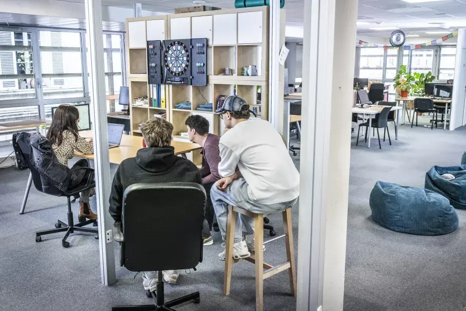 Photo d'un open space, avec des travailleurs autour d'une table et discutant.