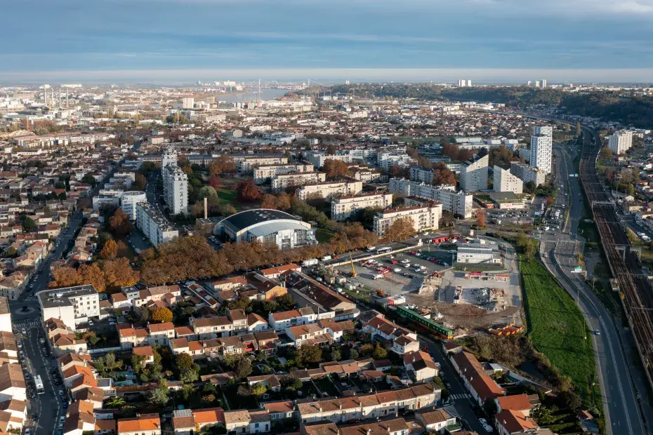 C’est une vue d’en haut d’un quartier avec des maisons, des immeubles, des routes et une voie ferrée.