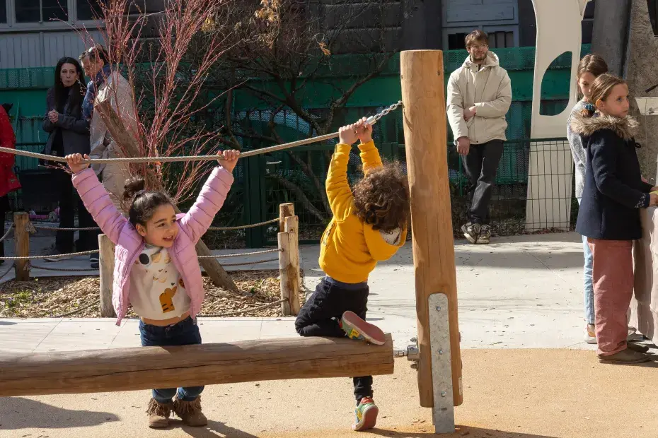 Des enfants qui jouent et des adultes qui discutent dans un cour d'école jouant,
