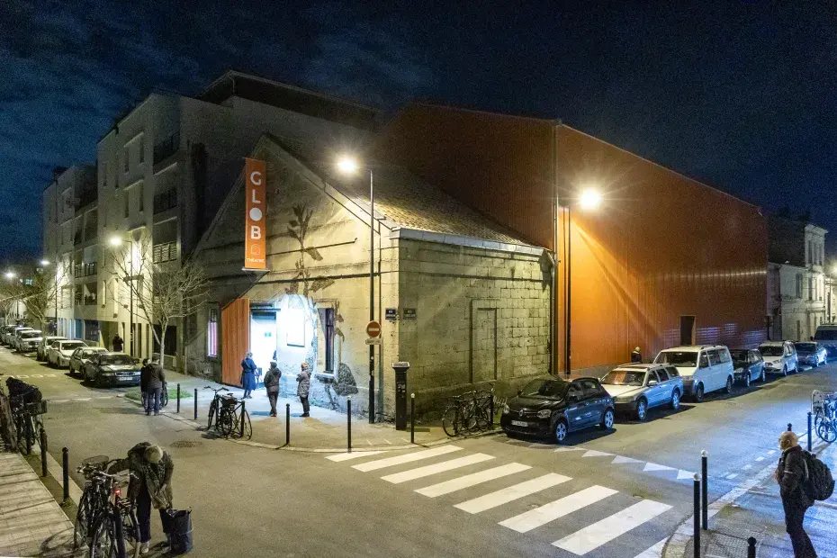 photo du glob théâtre d nuit et allumé, avec des passants et du public.