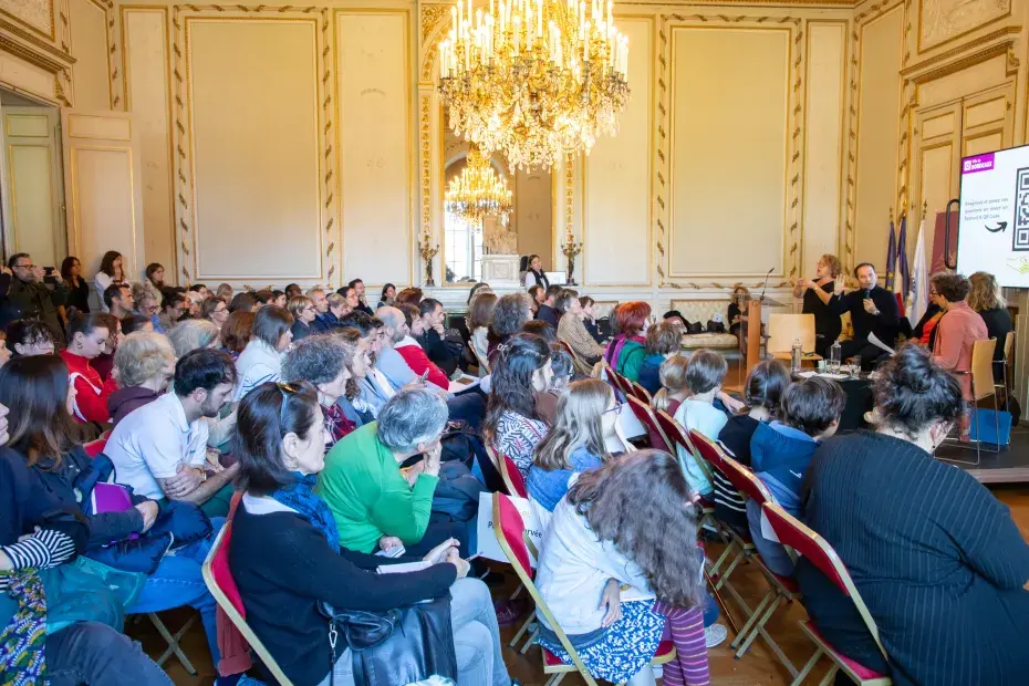 Photo d'une conférence organisée dans un salon de l'hôtel de ville de Bordeaux. A gauche, le public est assis. A droite, une estrade avec différents intervenants.