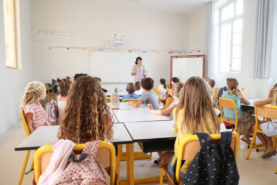 Des élèves écoutent leur enseignante dans une salle de classe.
