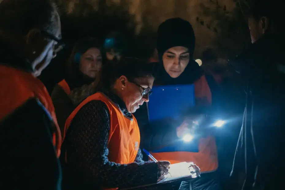 Photo d'une personne sans-abri et de 4 bénévoles qui remplissent un questionnaire à la lueur de 2 torches
