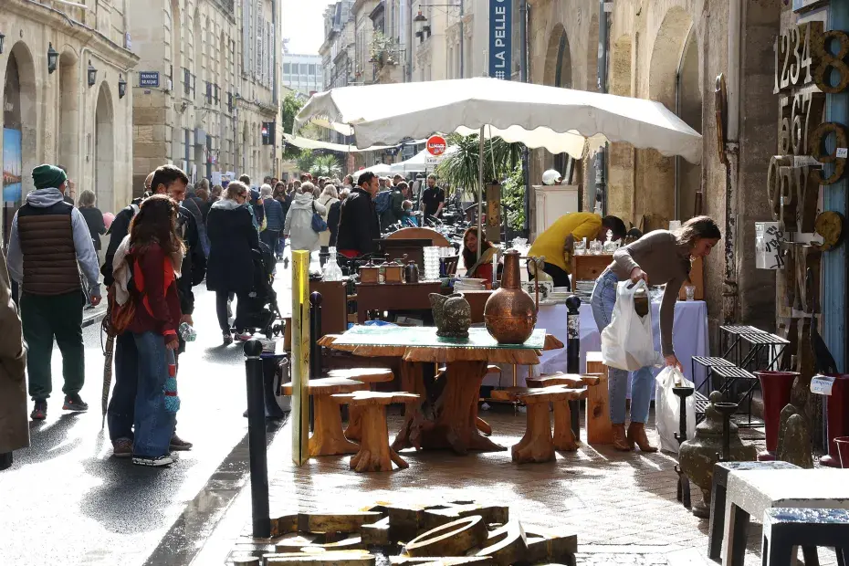 Des passants et des commerçant devant un terrasse dédiée à la brocante rue Notre-Dame