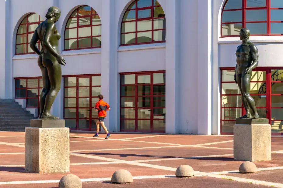Un homme qui cours à côté des statues du parc Lescure