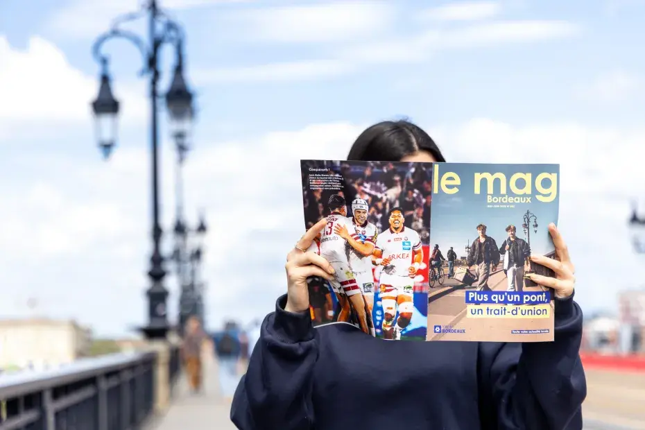 une femme lit le mg Bordeaux sur le pont de pierre