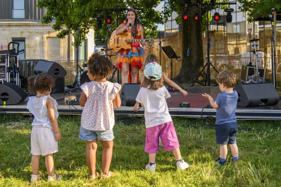 Quatre enfants dansant devant une chanteuse durant un concert au festival du grand parc
