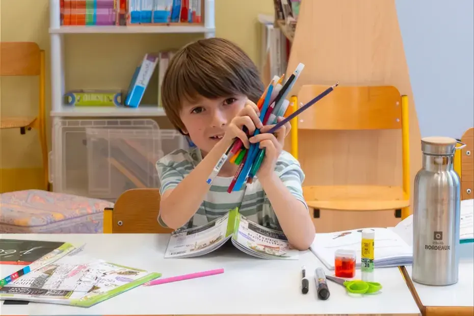 Un écolier souriant à son bureau avec des fournitures sur son bureau