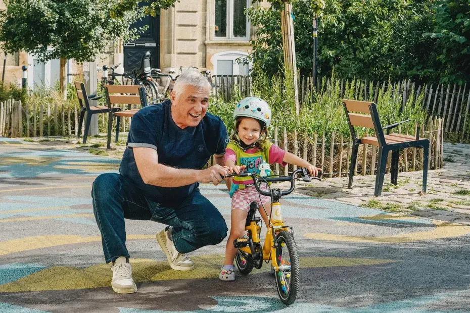 Une petite fille apprend à faire du vélo sur une place de Bordeaux