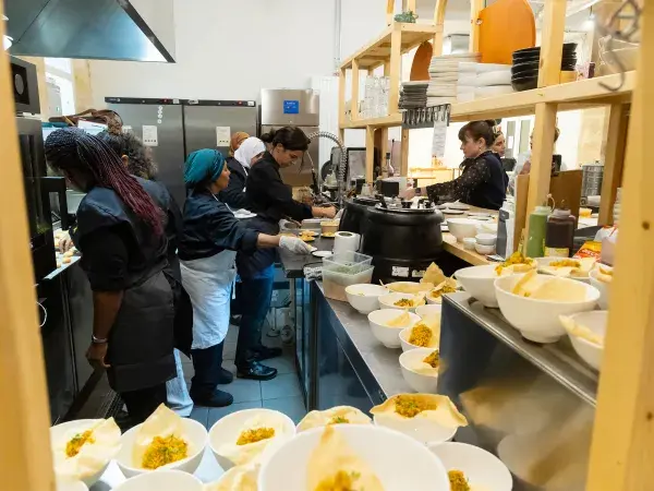 Des cuisinières préparant des plats dans la cuisine de la Manuco