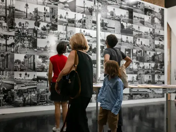 Quatre personnes regardent des photographies en noir et blanc sur un mur