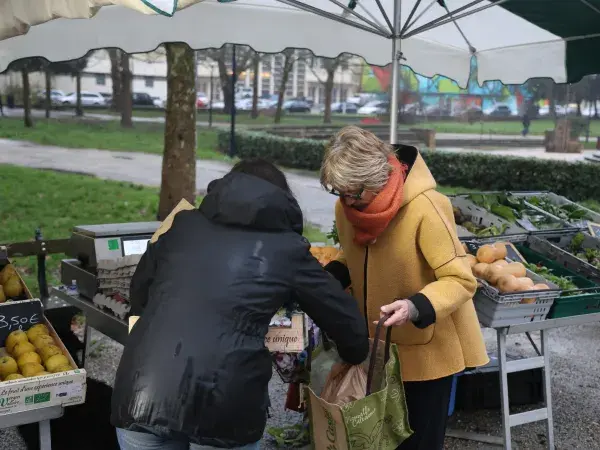 Une vendeuse des "Jardins Garonnais" aide sa cliente à ranger sa commande de fruits et légumes directement dans son cabas