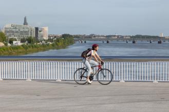 Photo d'une cycliste qui traverse à vélo le nouveau pont Simone Veil en direction de la rive droite.