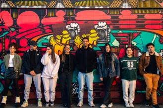 Un groupe de jeunes pose devant une fresque murale colorée