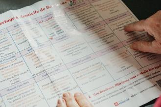 Des mains de personne âgée tiennent un menu.