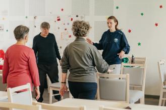 Trois seniors suivent un cours de sport avec une coach.