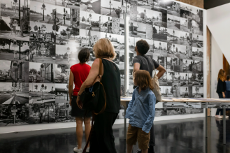 quatre personnes regardant des photographies en noir et blanc sur un mur